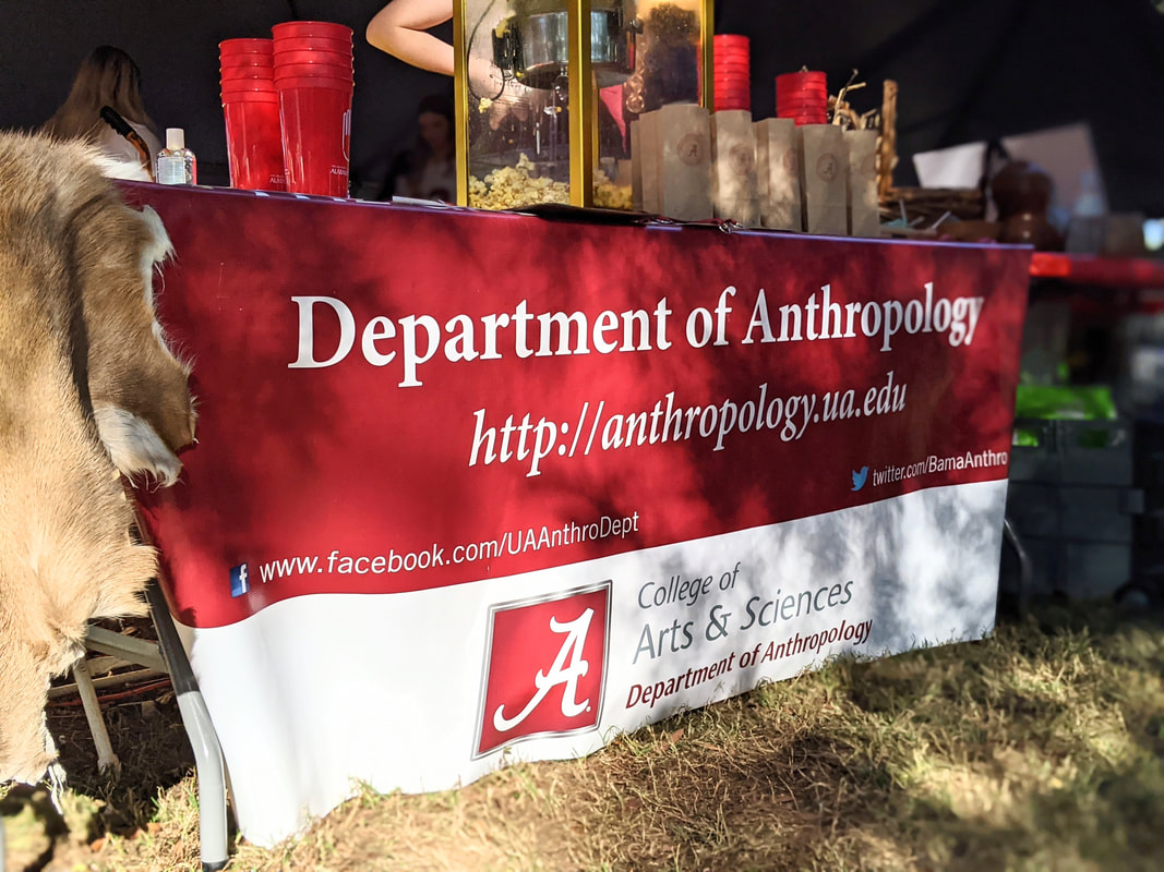 Banner for the Department of Anthropology with website address along a table with popcorn and drinks